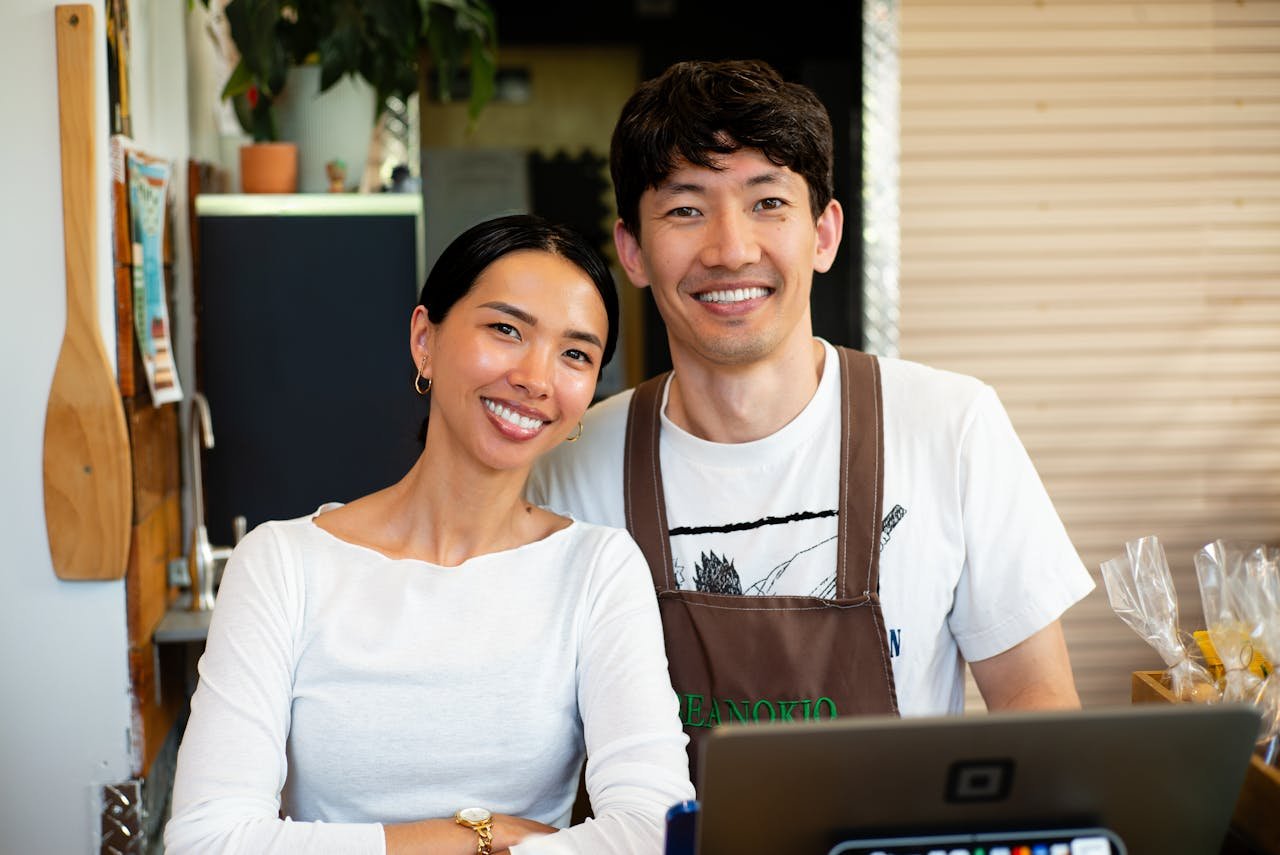 Cheerful cafe owners standing behind the counter in their welcoming coffee shop.